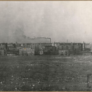 na pierwszym planie puste pole, w głębi wielokondygnacyjne kamienice