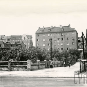 skrzyżowanie ulic, z lewej murowane ogrodzenie, w głębi kilkupiętrowa kamienica