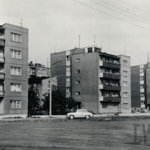 kilkupiętrowe bloki mieszkalne, przed nimi stoi samochód osobowy