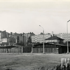 drewniane szopki ogrodzone drewnianym płotem, w głębi kilkupiętrowe budynki mieszkalne