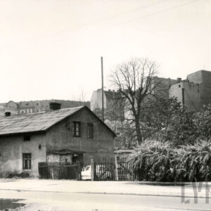 niski, otynkowany dom z drewnianym płotem