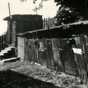 ciąg drewnianych komórek zamykanych na metalowe kłódki, w głębi drewniana komórka na podwyższeniu, do której prowadzą schodki