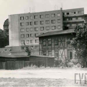 z prawej budynek drewniano-ceglany, za nim kilkukondygnacyjny otynkowany budynek mieszkalny 