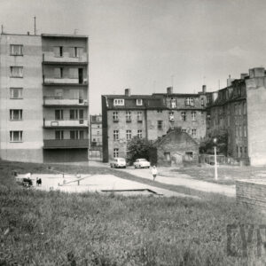 z lewej wielokondygnacyjny budynek mieszkalny, z prawej wielokondygnacyjny, ceglany, nieotynkowany budynek, przednim ceglany mały budynek