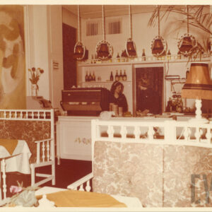 stylizowane na secesję wnętrze restauracji z białymi, tapicerowanymi ławkami i stolikami przykrytymi białymi obrusami i kolorowymi serwetami