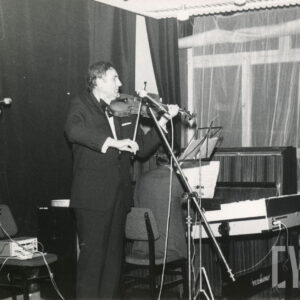 mężczyzna przy mikrofonie gra na skrzypcach