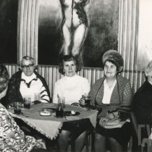 starsze osoby siedzą po kilka osób przy niskich stolikach