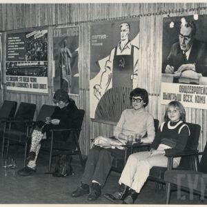 cztery osoby siedzą na fotelach pod ścianą, na ścianie propagandowe plakaty radzieckie