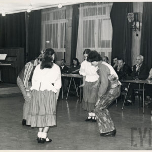 grupa seniorów siedzi przy stolikach pod oknem i ogląda pokaz taneczny