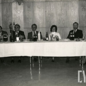 kobiety i mężczyźni siedzą przy stole nakrytym białym obrusem