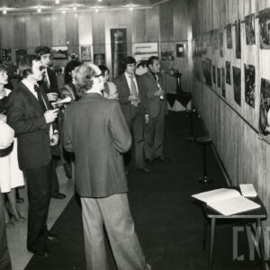 grupa ludzi oglądająca powieszone na ścianie fotografie