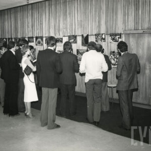 grupa ludzi oglądająca powieszone na ścianie fotografie