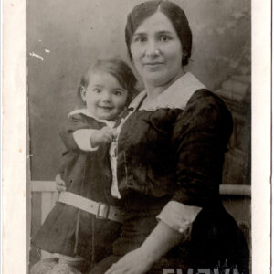 kobieta w ciemnej sukni z białym kołnierzem trzymająca na ręku małego chłopca