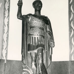 rzeźba mężczyzny w stroju wojskowym trzymającego krzyż w uniesionej ręce we wnętrzu kościoła