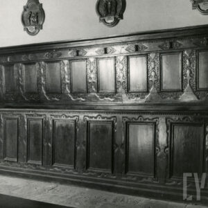 długa, zdobiona drewniana ławka z wysokim oparciem i osłoniętymi ozdobną płytą klęcznikami