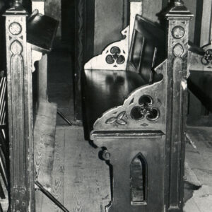 zdobiona rzeźbieniami na bokach drewniana ławka z klęcznikiem w kościelnym wnętrzu