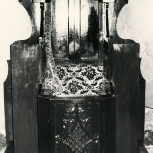 konfesjonał z ciemnego drewna ze zdobieniami i wzorzystym, wyściełanym siedziskiem