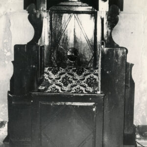 konfesjonał z ciemnego drewna ze zdobieniami i wzorzystym, wyściełanym siedziskiem