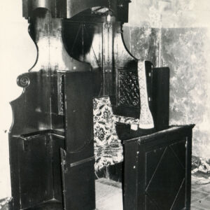 konfesjonał z ciemnego drewna ze zdobieniami i wzorzystym, wyściełanym siedziskiem