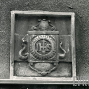 monogram z literami IHS w ozdobnym obramieniu na murze budynku