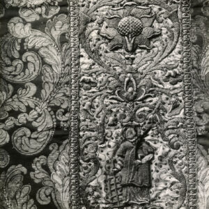 czarno-białe zdjęcie szaty liturgicznej haftowanej na całej powierzchni we wzór roślinny z figurami świętych w kolumnie środkowej 