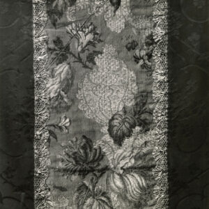czarno-biała fotografia fragmentu szaty liturgiczna z tłoczonego materiału z pionowym kwiecistym pasem pośrodku