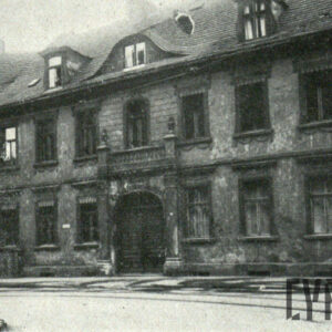 dwupiętrowa kamienica z cegieł, widoczne duże drzwi wejściowe oraz okna