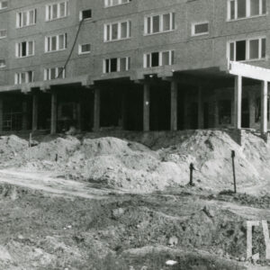 budowa bloku z wielkiej płyty, parterowa, zadaszona kondygnacja bloku, zadaszenie wsparte na filarach, przed blokiem kopce piachu