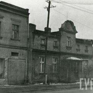 dwa przylegające do siebie domy, z prawej dwukondygnacyjny z ozdobnym szczytem, drewnianym gankiem, z lewej wyższy również dwukondygnacyjny z prostym dachem