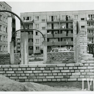 niska konstrukcja betonowo-ceglana zakończona metalowymi pałąkami, w głębi pięciokondygnacyjne bloki mieszkalne