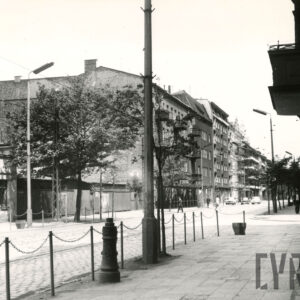 kilkukondygnacyjne budynki mieszkalne wzdłuż ulicy, z lewej parterowe pawilony