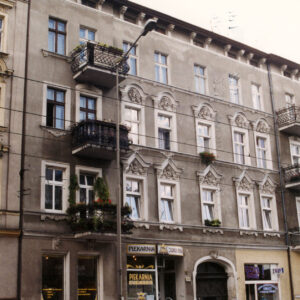 trzypiętrowa kamienica, przed nią zaparkowane samochody