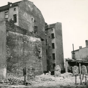 kilkukondygnacyjne kamienice od strony podwórza (ściany bez okien), przed nimi leży gruz