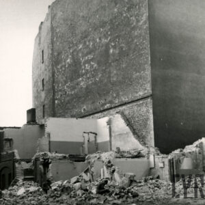 wysoka ściana bez okien kamienicy, przy niej pozostałości ścian rozbieranego budynku i gruz