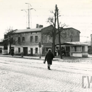 jednokondygnacyjne lub dwukondygnacyjne ceglane  budynki mieszkalne, na pierwszym planie brukowana ulica z torami tramwajowymi, z prawej kioski usługowe