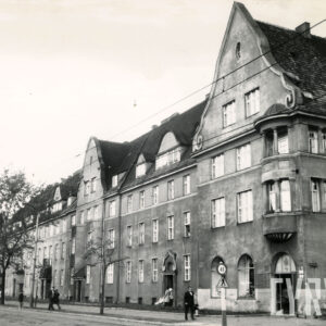 trzykondygnacyjne budynki z wykuszami i ozdobnymi szczytami oraz mieszkalnym poddaszem