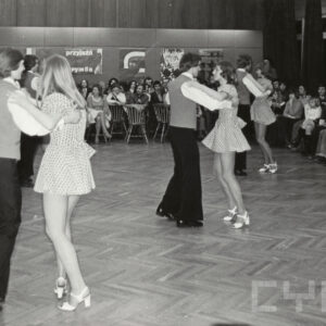 tańczące na parkiecie pary, dookoła nich siedzi publiczność