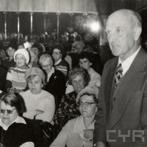 siedząca grupa starszych osób, z prawej stoi starszy mężczyzna