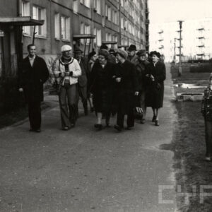 grupa ludzi idzie wzdłuż bloku