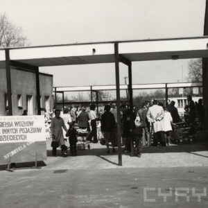 grupa ludzi stojąca między niskimi budynkami