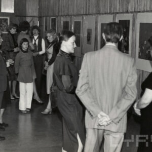 grupy ludzi rozmawiających ze sobą, w głębi na ścianie wiszą obrazy