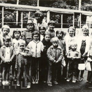 grupa dzieci z opiekunką na tle wagoników kolejki