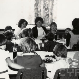 grupa dzieci z opiekunami siedzą przy stołach