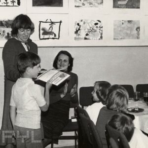 grupa dzieci z opiekunkami, na ścianie wiszą prace plastyczne dzieci