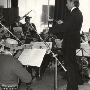 grupa muzyków w strojach ludowych, przed nimi dyrygent w garniturze