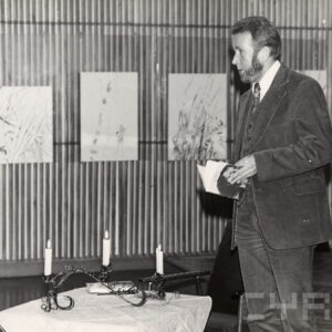 mężczyzna z brodą w garniturze stoi z książką w ręku