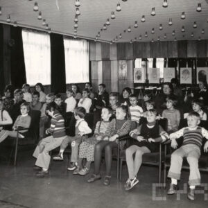 grupa dzieci siedzi na krzesłach w sali