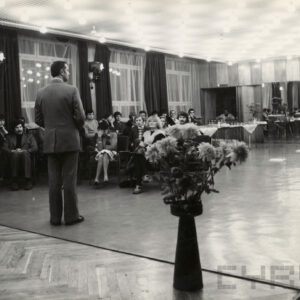 grupa ludzi siedzi i słucha zwróconego do nich mężczyzny