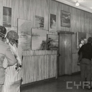 ludzie oglądają obrazy powieszone na  ścianie