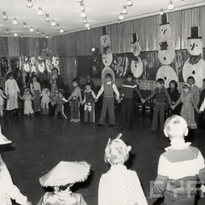 grupa dzieci stoi w kole, trzymając się za ręce, część z nich przebrana